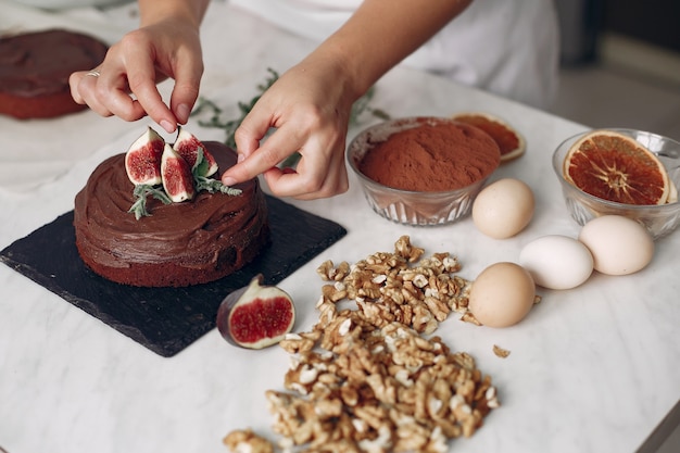 Foto gratuita lo chef in abiti bianchi prepara una torta al cioccolato. la signora sta preparando il dessert. la donna cuoce una torta.