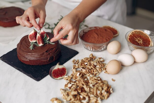 白い服を着たシェフがチョコレートケーキを用意します。女性はデザートを準備しています。女性はケーキを焼きます。