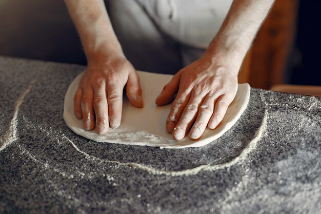 흰색 유니폼을 입고 요리사는 pizzaa를 준비