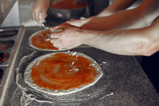 흰색 유니폼을 입고 요리사는 pizzaa를 준비