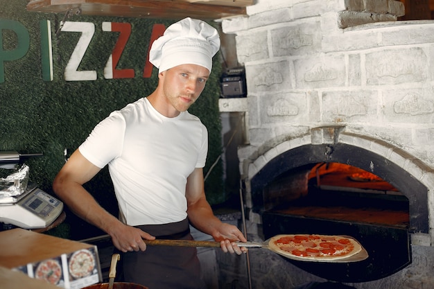 Chef in a white uniform prepare a pizzaa