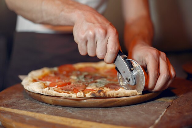 Chef in a white uniform prepare a pizzaa