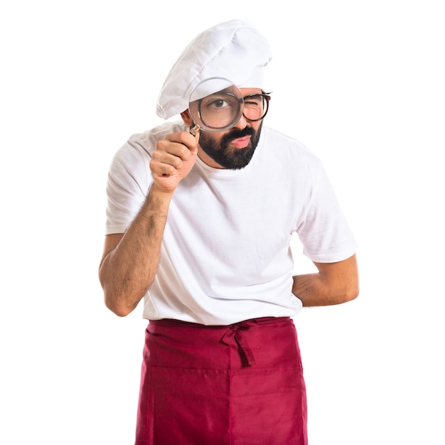 Chef with magnifying glass over white background