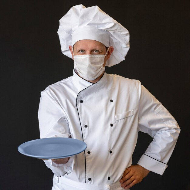 Chef with medical mask holding plate