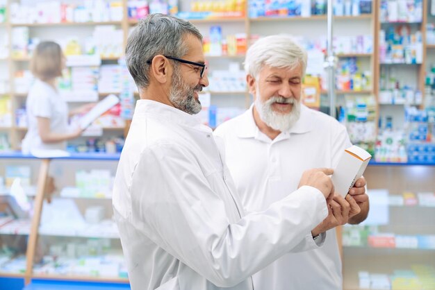 Chemist explaining prescription to senior man in drugstore