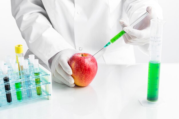 chemist injecting apple with chemicals in tubes