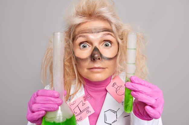 화학자 조사관은 보호용 고글을 착용한 후 놀란 것처럼 보이는 녹색 액체가 담긴 유리 제품을 들고 눈 주위에 더러운 흔적이 있습니다. 실험 수행 후 실험실에서 폭발