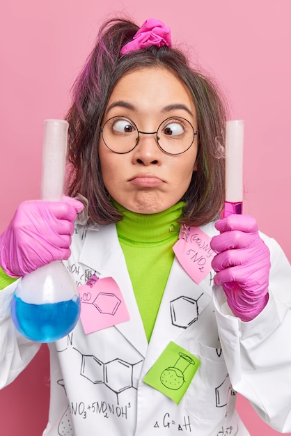 Foto gratuita il chimico fa una smorfia in giro mentre lavora in laboratorio impazzisce esegue la ricerca tiene la vetreria con una soluzione liquida mescola agenti chimici durante l'esperimento