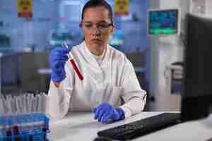 Free photo chemist researcher holding test tubes with patient blood working at disease diagnostic in biochemical hospital laboratory. doctor developing medical vaccine against covid19 during chemistry experiment