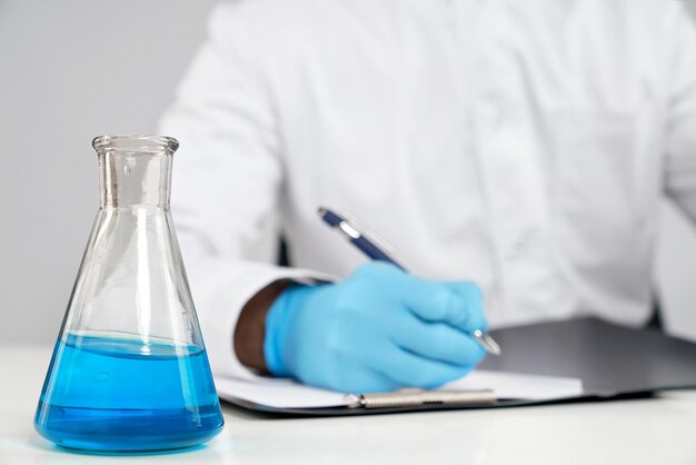 Chemist writing report flask nearby