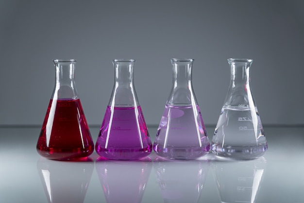 Chemistry flasks in a row with different colored dangerous toxic liquid in them
