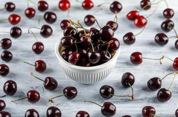 Cherries in a bowl on a grunge surface. high angle view.