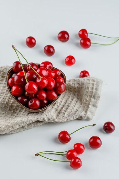 Cherries in a bowl high angle view on white and kitchen towel