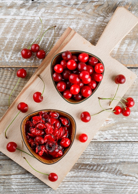 Free photo cherries in a bowl with jam on wooden and cutting board