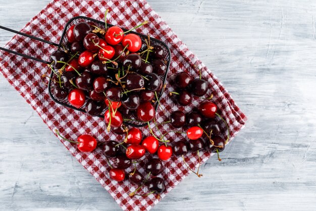 Cherries in a cullender on grunge and picnic cloth surface. flat lay.