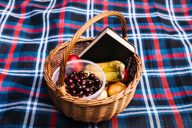 Foto gratuita ciliegie; frutta e libro nel cestino sulla coperta