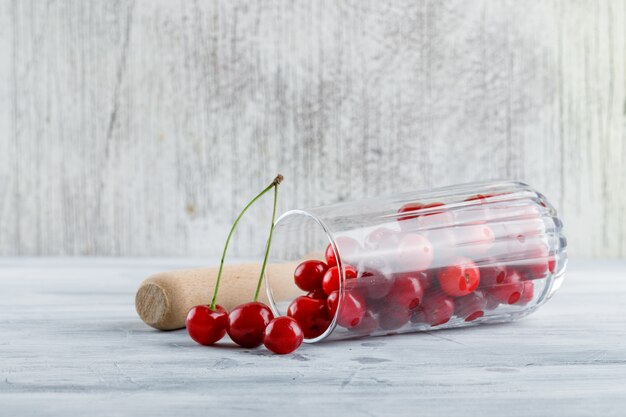 Cherries in a glass jug side view on a grungy grey