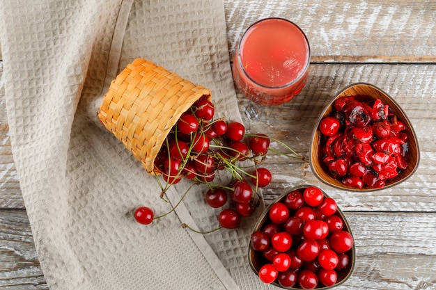 Cherries with cocktail, jam in bowl and basket on wooden and kitchen towel