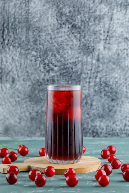 Cherries with cutting board, juice on plaster and grungy space, side view.