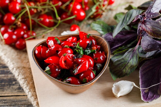 Cherries with jam, garlic, basil, cutting board on wooden and piece of sack