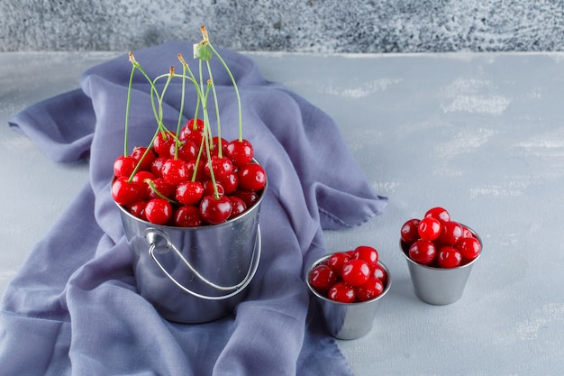 Free photo cherries with textile in buckets, high angle view.