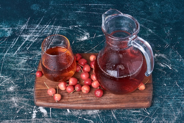 Free photo cherry berries with a cup of drink on blue.