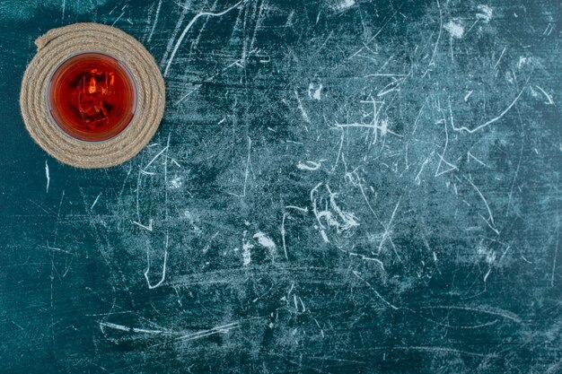 Cherry juice in a glass on trivet, on the marble background.