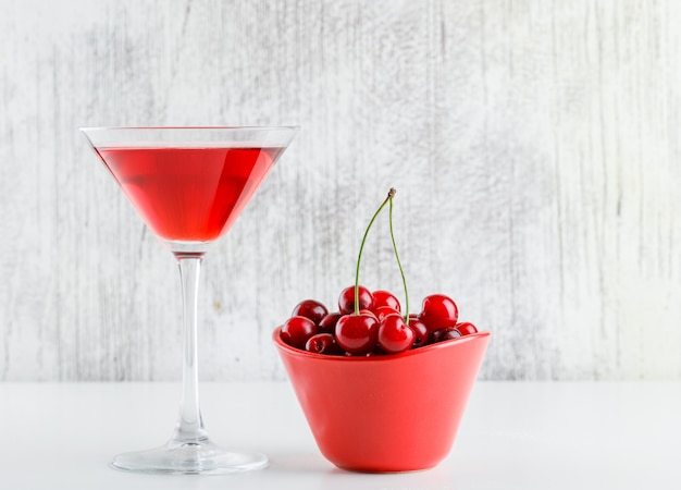 Cherry juice with cherries in a glass on white