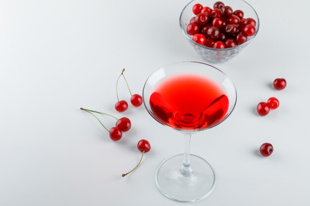 Cherry juice with cherries in a glass on white