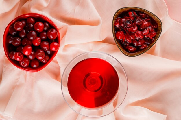 Cherry juice with cherries, jam in a glass on pink and textile