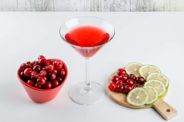 Cherry juice with cherries, lemon in a glass on white