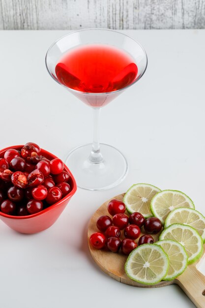 Cherry juice with cherries, lemon slices in a glass on white