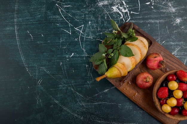 Cherry plate with pomegranate and pears on a wooden platter in the corner