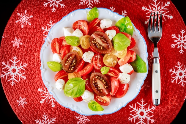 Салат из помидоров черри и моцареллы с вилкой на рождественский ужин. вегетарианское блюдо.