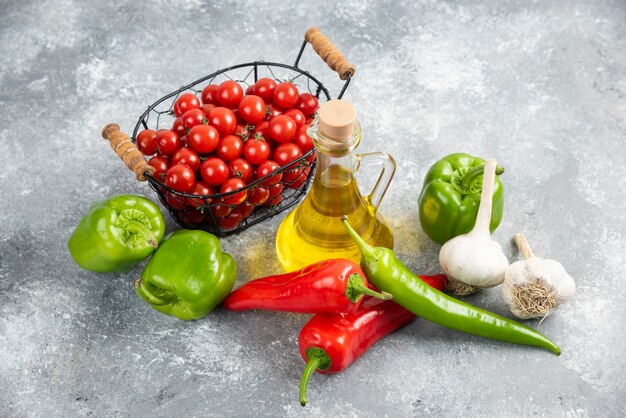 Cherry tomatoes in basket with chili peppers, garlic and olive oil.