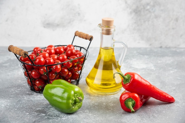 Cherry tomatoes in basket with chili peppers and olive oil.