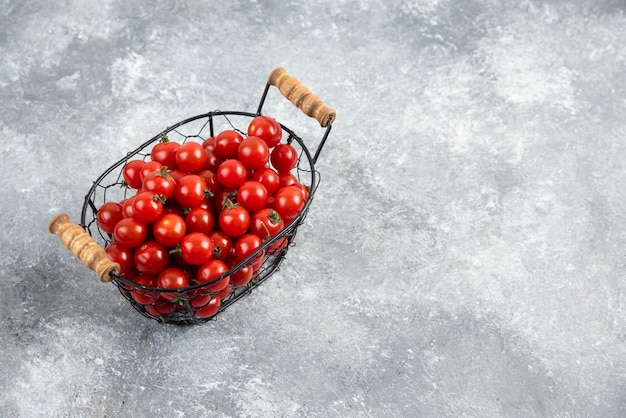 Cherry tomatoes in a metallic basket on marble table