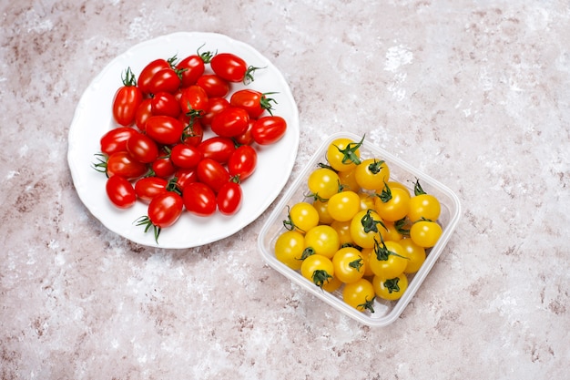 Foto gratuita pomodori ciliegia di vari colori, pomodori ciliegia gialli e rossi su sfondo chiaro
