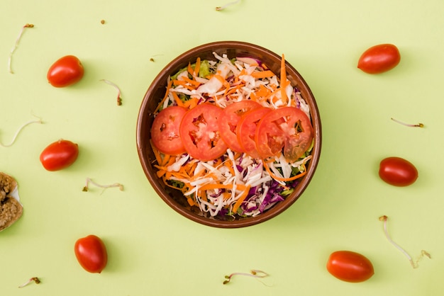 Foto gratuita pomodori ciliegia con insalatiera grattugiata e pomodori su sfondo verde menta