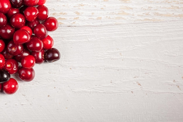 Free photo cherry on white wooden background with copyspace available. healthy raw fruits