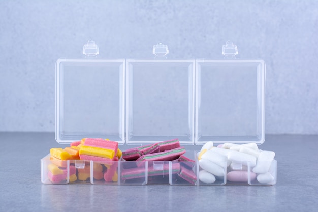 Free photo chewing gum cubes, strips and tablets neatly sorted into small boxes on marble surface