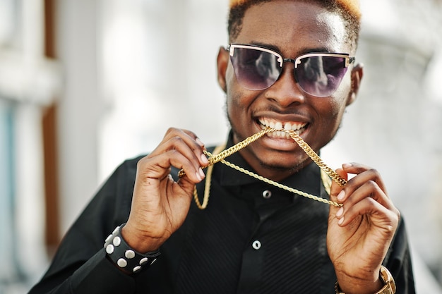 Chic handsome african american man in black shirt with gold chain and sunglasses