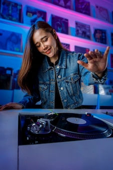 Chica dj latina mezclando musica en una tienda de discos con un tornamesa y discos de vinil