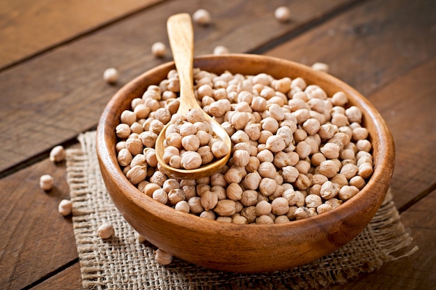 Chick-pea in wooden bowl on wooden table close up