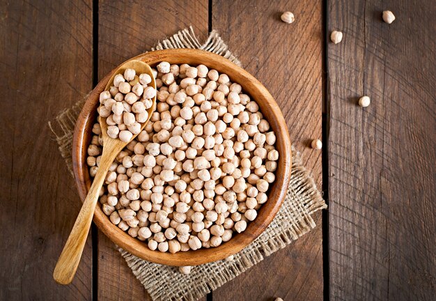 Chick-pea in wooden bowl on wooden table close up