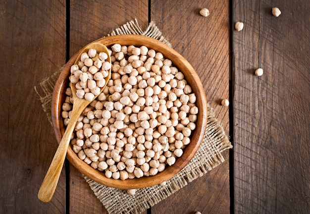 Chick-pea in wooden bowl on wooden table close up