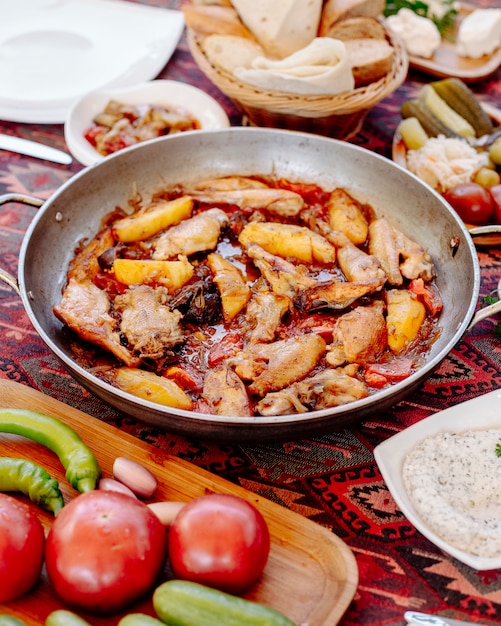 Бесплатное фото Курица и картофель на гриле в масляном соусе на сковороде, овощи вокруг.