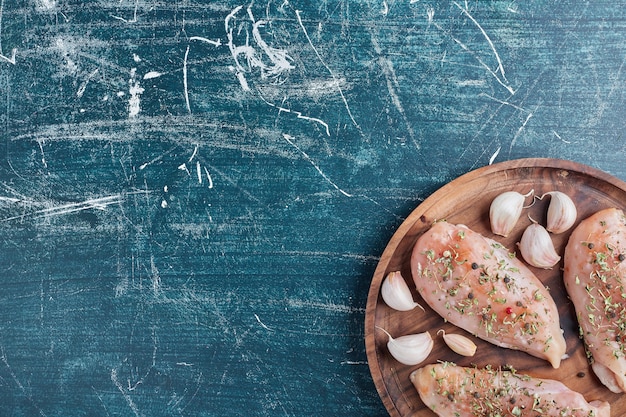 Chicken breast on a wooden board with garlic.