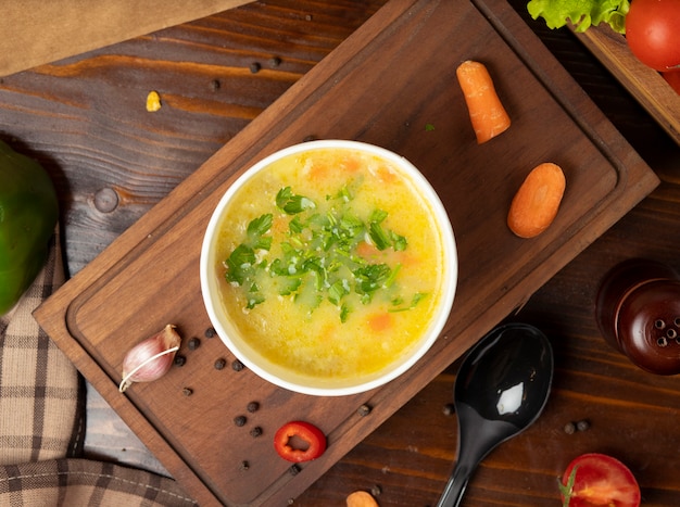 Chicken broth vegetable soup in disposable cup bowl served with green vegetables    