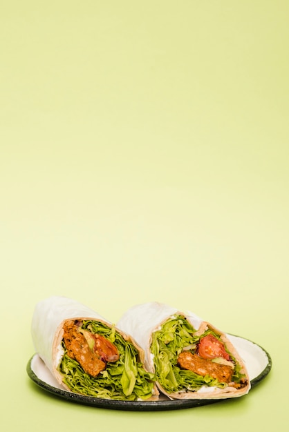 Chicken burrito wrap on plate against mint green background